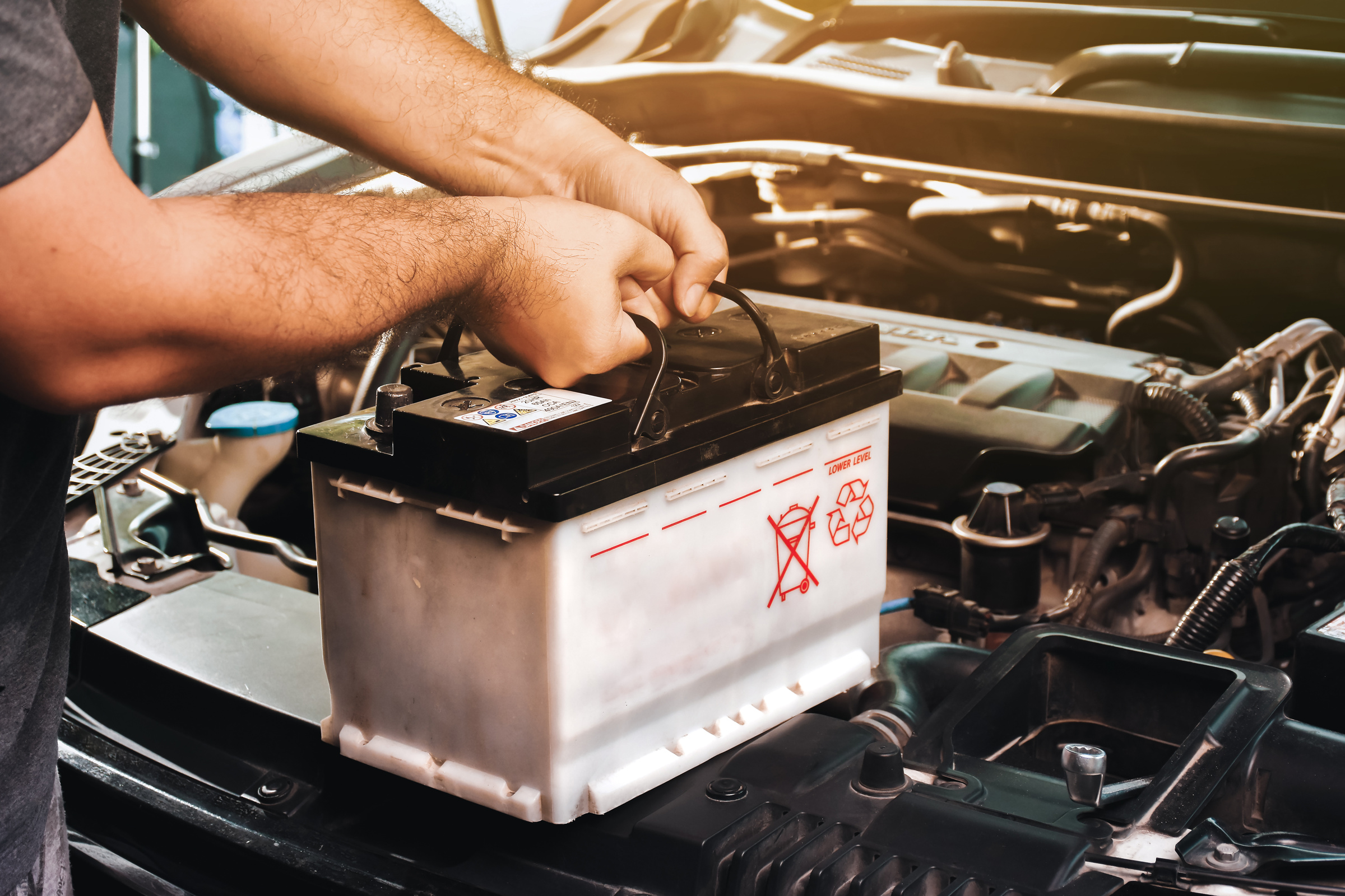 A auto mechanic carries a replacement car battery for car electr